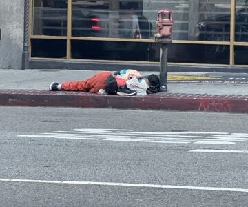 homeless man sleeping on a los angeles sidewalk