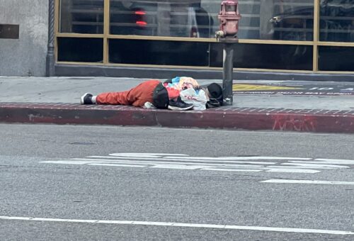 homeless man sleeping on a los angeles sidewalk